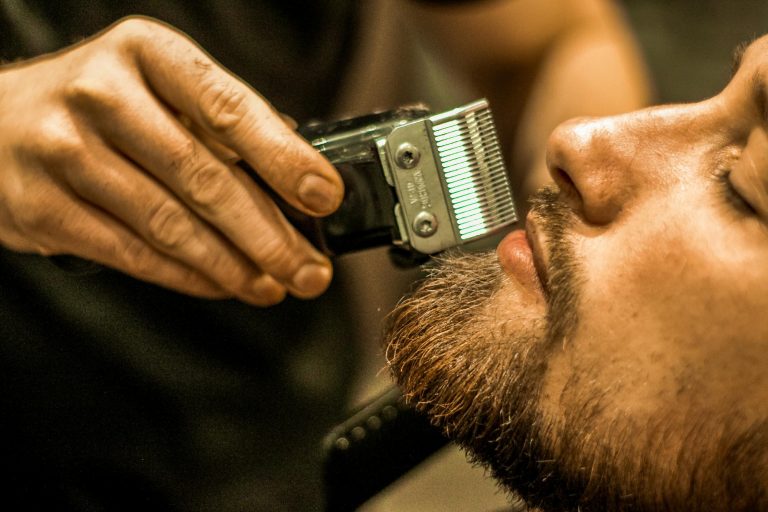 Barber przycina brodę maszynką z nasadką
